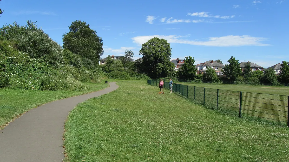 A fenced dog park next to a paved path